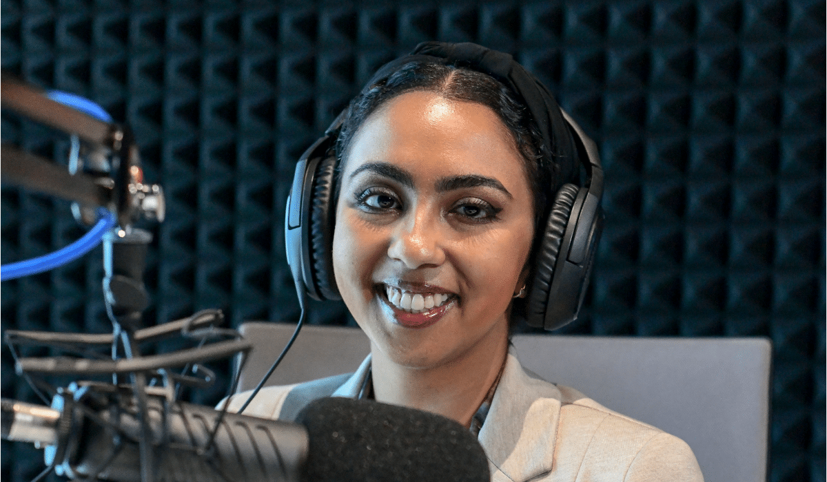 A picture of podcaster Doaa Farid wearing headphones and sitting in front of a microphone