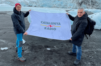Two engineers from Catalunya Ràdio hold a flag with the radio station's name in Antarctica