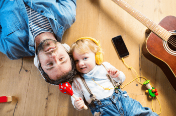 A child and its father lying down with headphones on