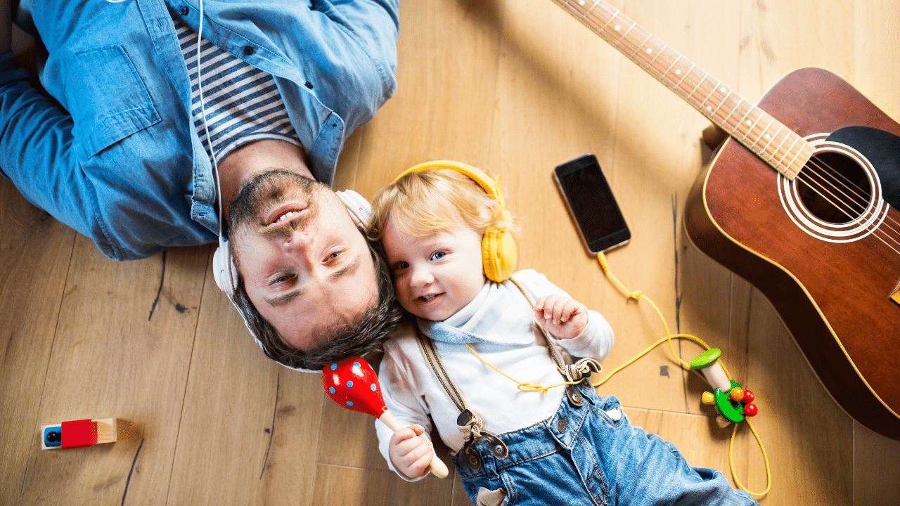 A child and its father lying down with headphones on
