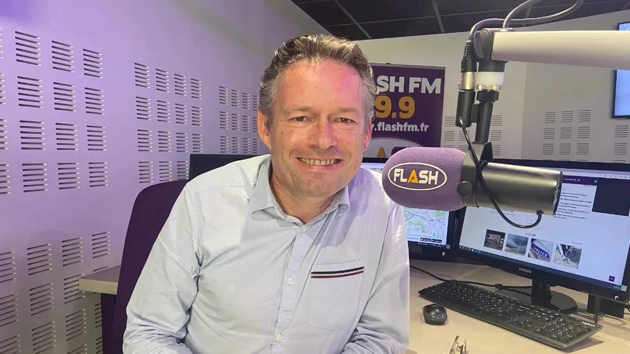 Flash FM’s Managing Director Pascal Thomas in a radio studio, next to a microphone which says "Flash FM " on it