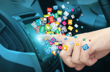 A finger touches a car touchscreen, releasing a variety of multicoloured icons